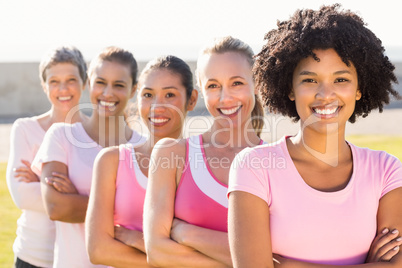 Smiling women wearing pink for breast cancer with arms crossed