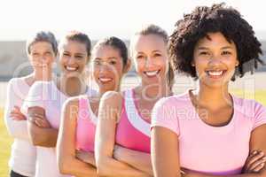 Smiling women wearing pink for breast cancer with arms crossed