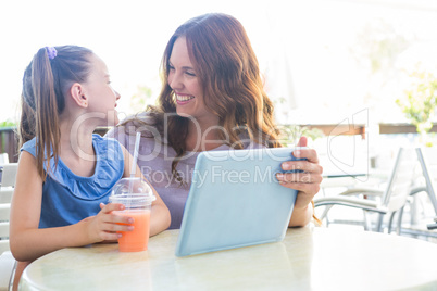 Mother and daughter using tablet at cafe terrace