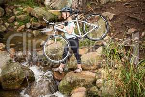 Profile view of a fit woman lifting her bike