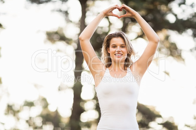Pretty young jogger shaping heart with hands
