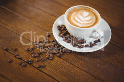 Cup of cappuccino with coffee art and coffee beans