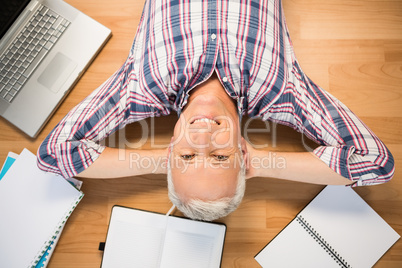 Smiling man lying on floor surrounded by office items