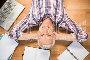 Smiling man lying on floor surrounded by office items