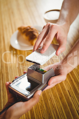 Paying for a croissant and a coffee with his smartphone