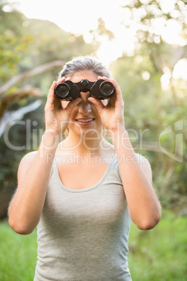 Smiling pretty brunette looking through binoculars