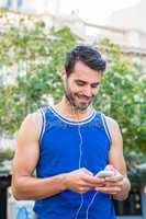 Handsome athlete smiling and using smartphone