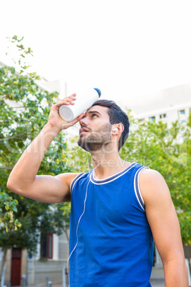 Handsome athlete cooling his forehead with bottle