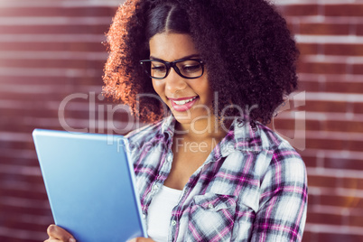 Attractive hipster smiling and looking at tablet