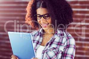 Attractive hipster smiling and looking at tablet