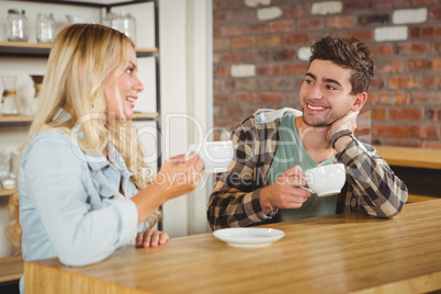 Smiling hipsters talking and enjoying coffee together