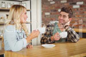 Smiling hipsters talking and enjoying coffee together