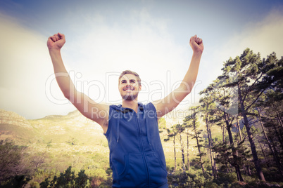 Young happy jogger standing on rock and cheering