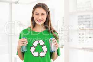 Smiling eco-minded brunette holding recycling bottles