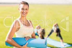 Smiling sporty brunette in front of friends doing exercises