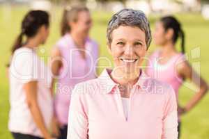 Smiling woman wearing pink for breast cancer in front of friends