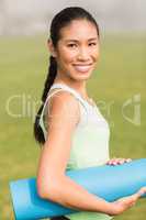 Smiling sporty woman holding exercise mat