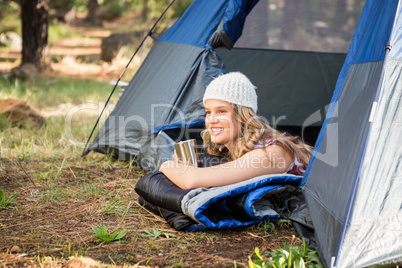 Pretty blonde camper smiling and lying in tent