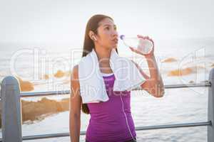 Fit woman resting and drinking water at promenade