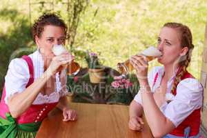 Zwei attraktive bayerische Frauen trinken Bier