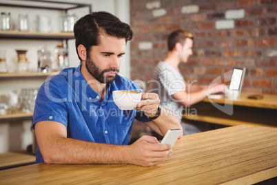 Young man enjoying a coffee and using his smartphone