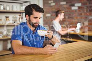 Young man enjoying a coffee and using his smartphone