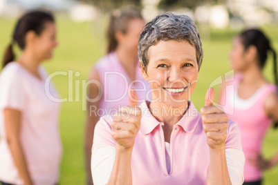 Smiling woman wearing pink for breast cancer in front of friends