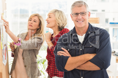 Businessman with arms crossed with his team behind