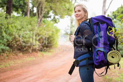 Smiling female hiker waiting by the side of the road