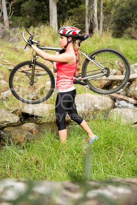 Blonde athlete carrying her mountain bike