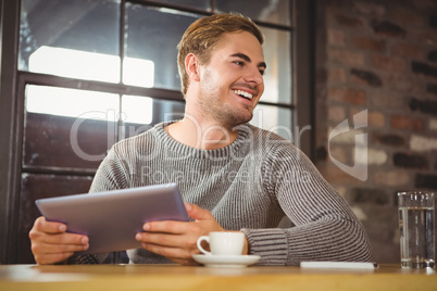Handsome man smiling and holding tablet computer