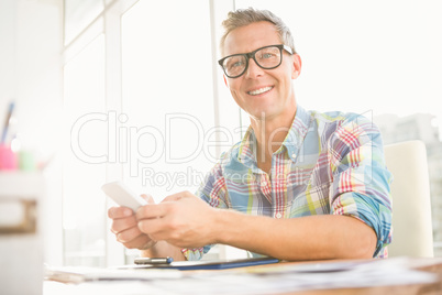 Smiling casual designer using smartphone