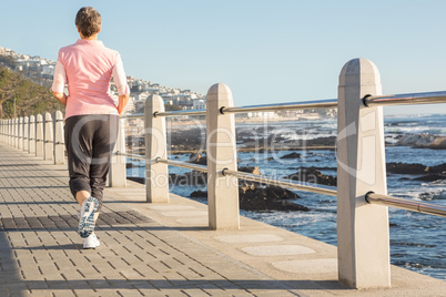 Rear view of sporty woman jogging at promenade