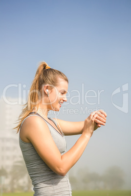Smiling sporty blonde using smart watch