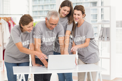 Smiling volunteers pointing on laptop