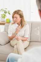 Unhappy woman sitting on couch and talking to therapist
