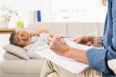 Therapist listening to male patient and taking notes