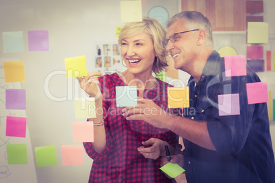 Smiling business team pointing post its on the wall