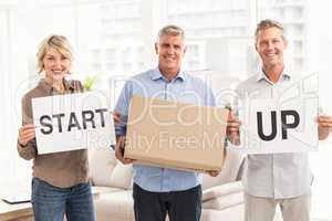 Smiling casual business people holding start up sign