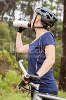Athletic blonde drinking and holding mountain bike