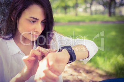 Beautiful brunette using smartwatch in the park