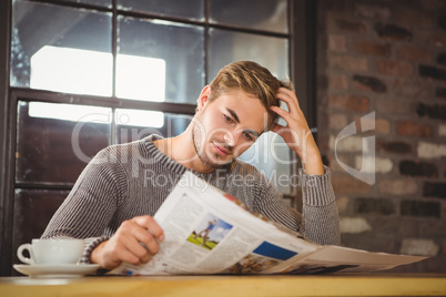 Handsome man having coffee and reading newspaper