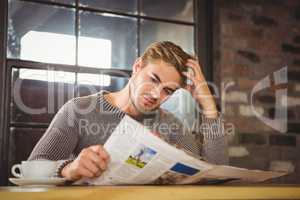 Handsome man having coffee and reading newspaper