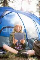 Pretty blonde camper using tablet and sitting in tent