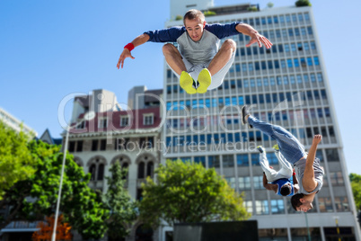 Happy friends doing parkour in the city