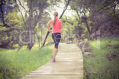 Blonde athlete jogging on wooden path