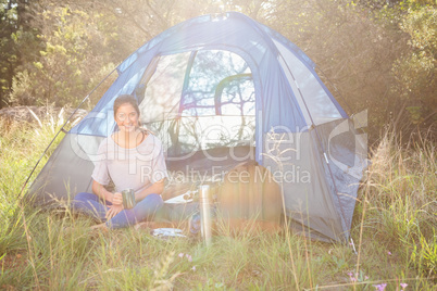 Smiling brunette camper sitting in tent