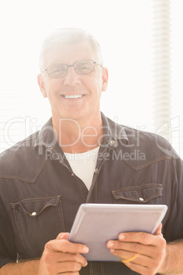 Smiling businessman holding a digital tablet