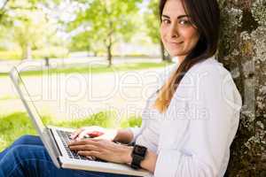 Beautiful brunette using laptop in the park