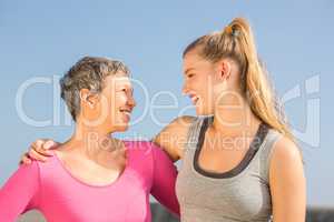 Sporty mother and daughter smiling at each other